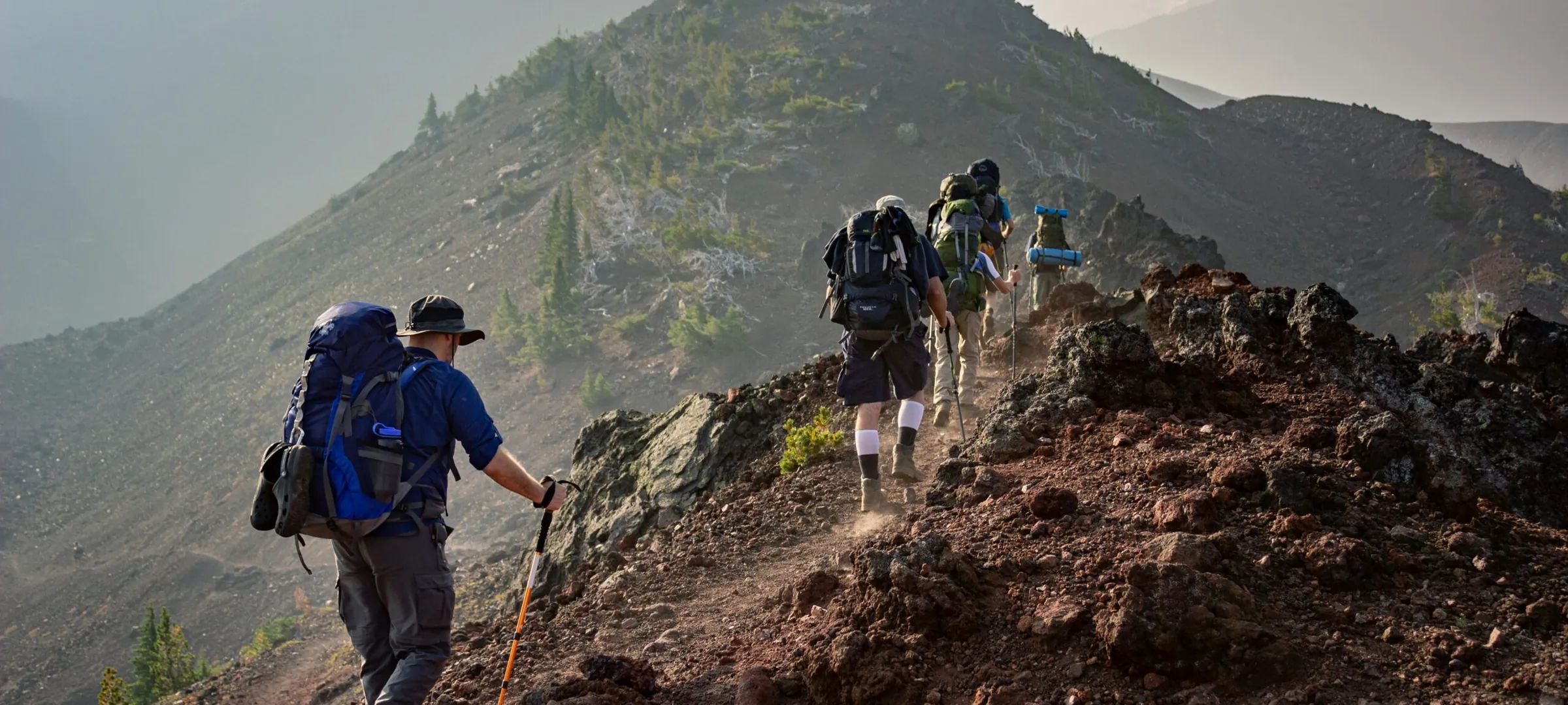 Trekkers on a ridge trail with packs, on a graded route.